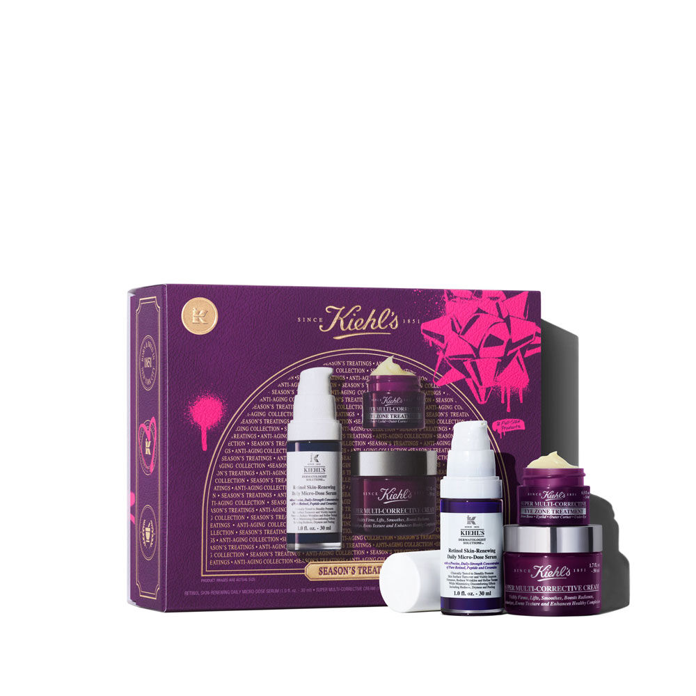 Una imagen grafica que muestra una caja rectangular de regalo de Kiehl's en tonos morado y rosa, titulada "SEASON'S TREATINGS ANTI-AGING COLLECTION". Delante de la caja, hay una botella blanca y morada de Retinol Skin-Renewing Daily Micro-Dose Serum, un pequeno tarro morado de Super Multi-Corrective Eye Zone Treatment y un tarro morado mas grande de Super Multi-Corrective Cream