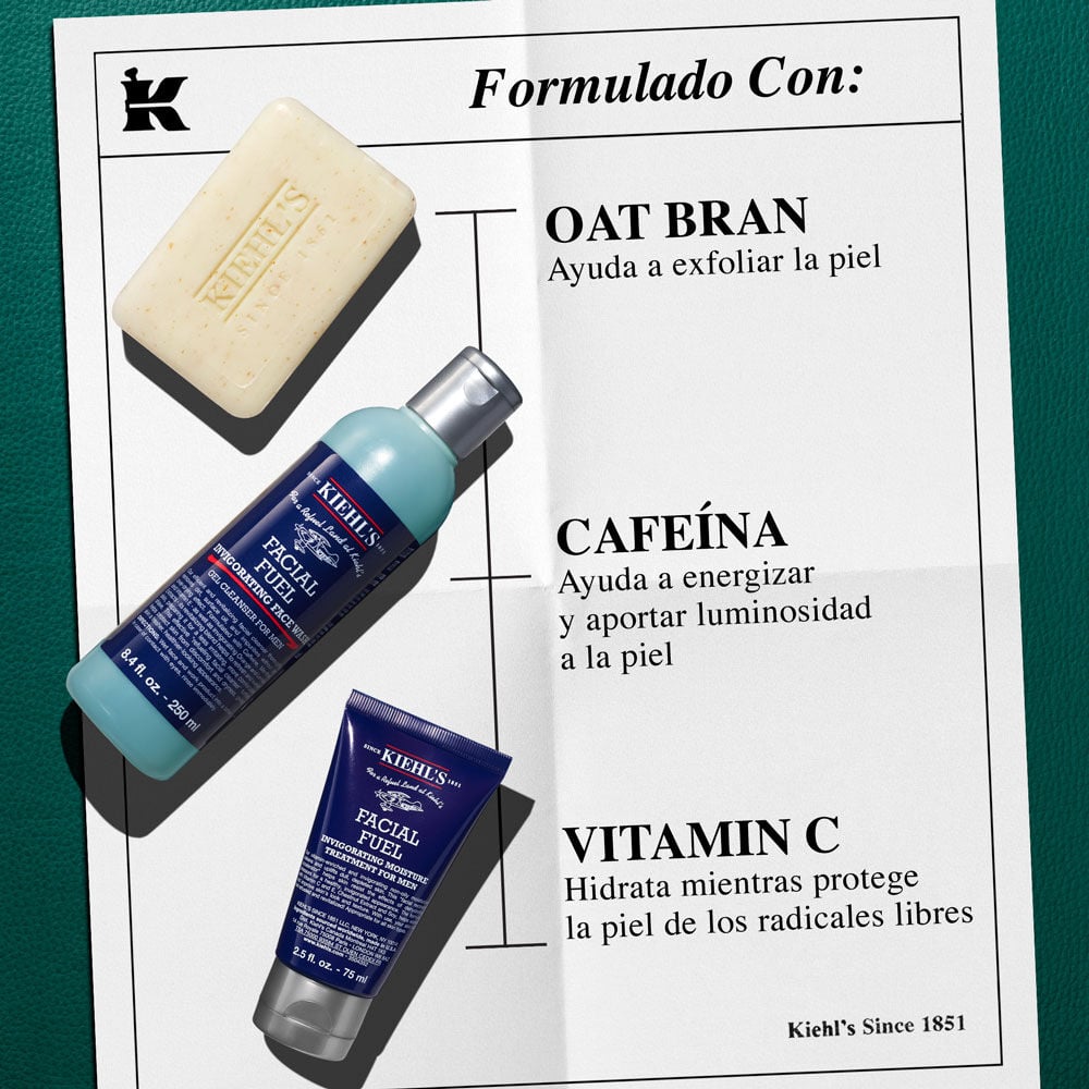 Un grafico de papel blanco sobre fondo verde oscuro. Tres productos Kiehl's en diagonal con "Nuestros Productos Con:". Jabon corporal (SALVADO DE AVENA: Exfolia). Gel facial (CAFEINA: Revitaliza). Humectante (VITAMINA Cg: Luminosidad). Con logo 'K'.