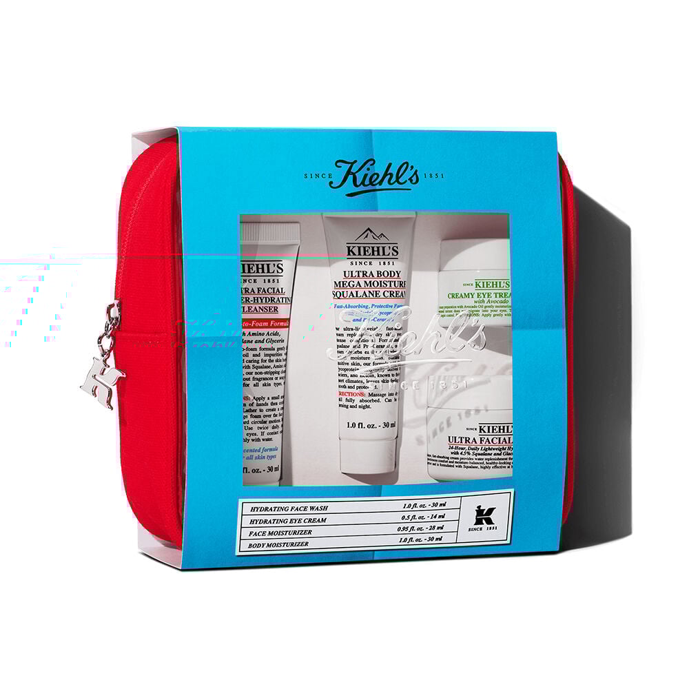 Set de regalo de viaje Kiehl's en estuche rojo. Incluye varios productos visibles a traves de una ventana con diseno en tonos azules.