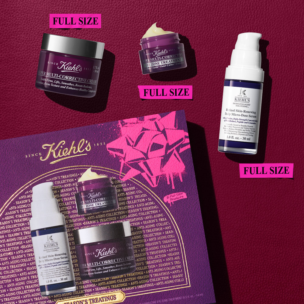 Un set de regalo Kiehl's 'SEASON'S TREATINGS ANTI-AGING COLLECTION' abierto, de color morado y rosa, que exhibe tres productos de tamano completo: un frasco blanco y morado de Retinol Skin-Renewing Daily Micro-Dose Serum, un pequeno tarro morado de Super Multi-Corrective Eye Zone Treatment y un tarro morado mas grande de Super Multi-Corrective Cream.
