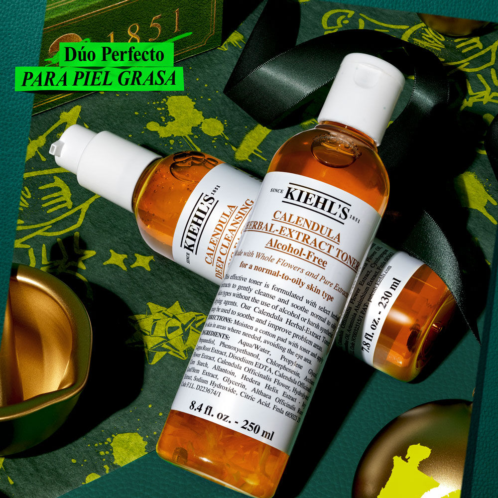 Un grafico festivo sobre fondo verde y dorado, muestra dos botellas: "KIEHL'S CALENDULA DEEP CLEANSING FOAMING FACE WASH" y "KIEHL'S CALENDULA HERBAL-EXTRACT TONER", ambas con liquido ambar. Arriba a la izquierda, una etiqueta verde dice "¡Regala PIEL CALMADA esta Navidad!".