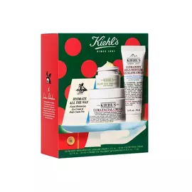 Estuche de regalo de cuidado de la piel navideno de Kiehl's que incluye la crema Ultra Facial Cream, el tratamiento para contorno de ojos Creamy Eye Treatment with Avocado y la crema corporal Ultra Body Mega Moisture Squalane Cream en una caja festiva con lunares rojos y verdes.