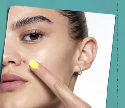 Mujer senalando una imperfeccion en su rostro